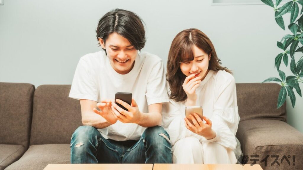 部屋でスマホを使う男女