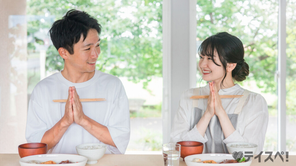 食事を前に笑顔でいただきますをする若い夫婦（カップル）