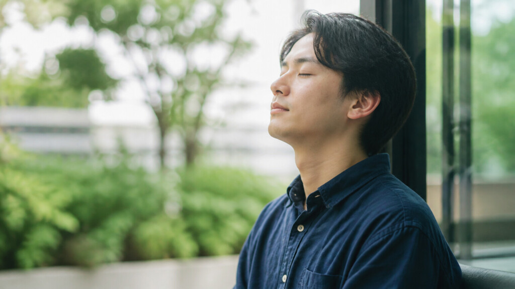 深呼吸で気持ちを落ち着かせる30代男性